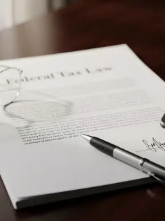 Estate planning documents with pen and calculator, symbolizing tax law changes.